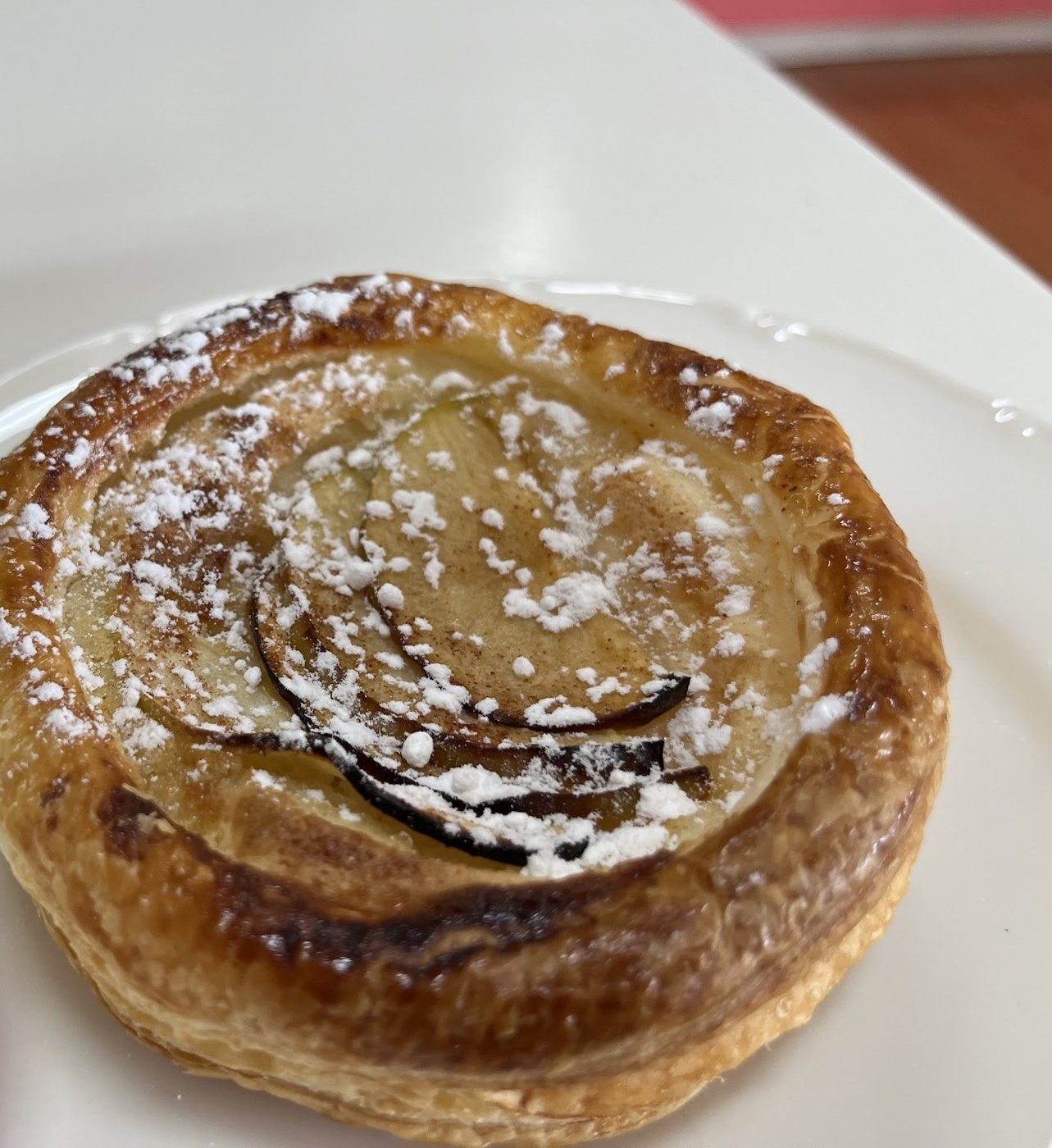 An apple pastry tart dusted with icing sugar