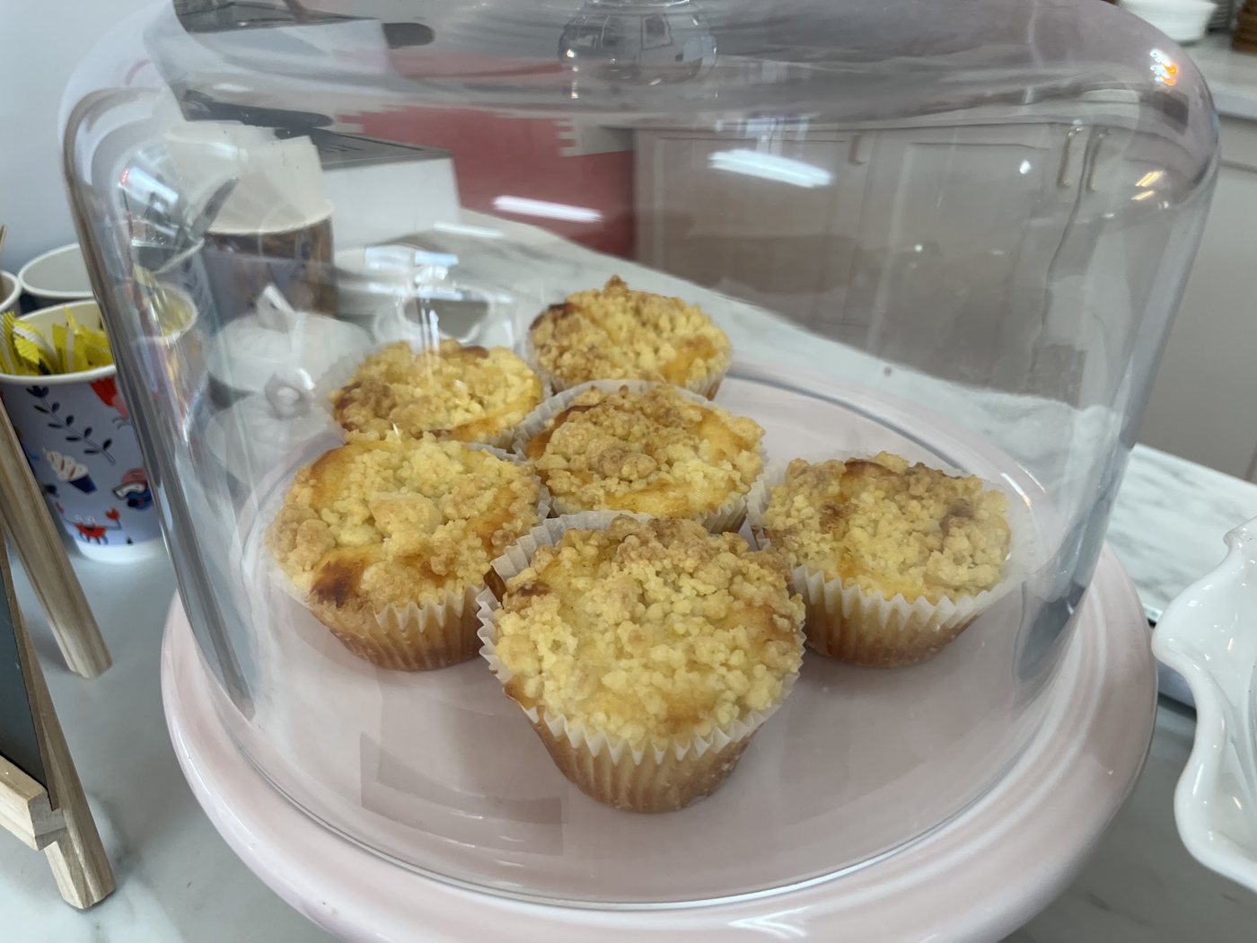 Lemon crumble muffins under a glass cake dome