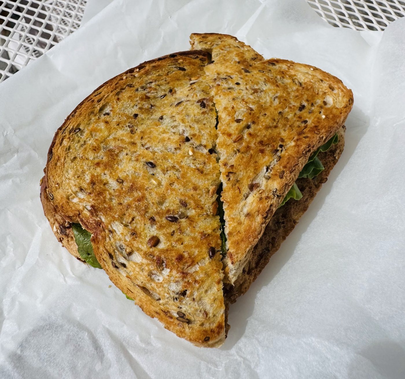 A toasted seeded-grain sandwich with salad, cut in half