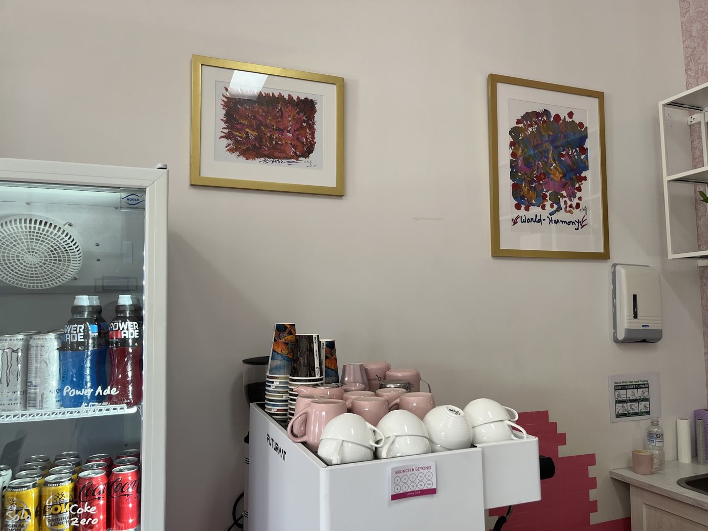Framed artwork above the cup station, with pink and white cups ready to go